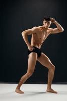 athletic man with a pumped up naked torso in dark panties posing photo
