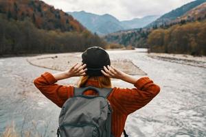 mujer viaje en el montañas en naturaleza en otoño cerca el río y mochila sombrero suéter vacaciones foto