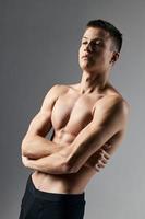 sexy bodybuilder crossed arms over chest on gray background cropped view photo