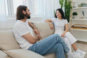 Man and woman friends sitting on the couch and smiling merrily talking to each other having a good time together. Lifestyle in happiness at home photo