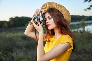 mujer fotógrafo en sombrero mirando dentro el cámara lente sonrisa naturaleza pasatiempo foto