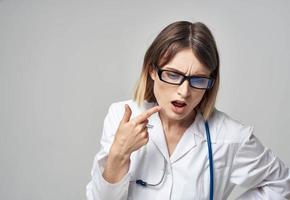 médico en un médico vestido con un estetoscopio alrededor su cuello perplejo Mira gris antecedentes foto