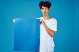 Cheerful guy with curly hair blue mockup poster advertising isolated background photo