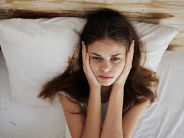 woman lying on the bed hands on face feeling unwell photo