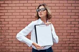 cheerful woman manager in white shirt documents in hands brick background photo