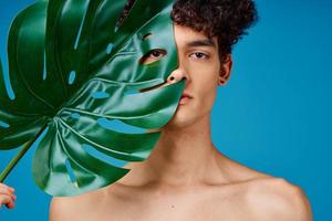handsome man with curly hair naked shoulders green leaf clear skin photo