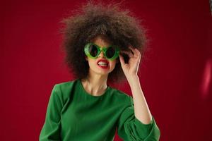 mujer con Rizado peinado con Gafas de sol en un rojo antecedentes emociones foto