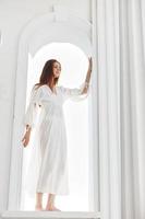 Woman in a white dress in the opening in the form of an arch posing photo