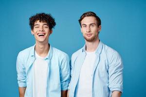 dos amigos en idéntico camisas y un camiseta gesticulando con su manos en un azul antecedentes foto