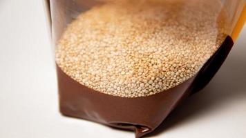 Quinoa seeds in a plastic container on a white background closeup photo