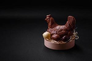 Chocolate Easter hen and eggs in a nest with straw photo