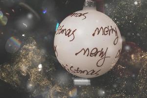 white bauble with red inscription merry christmas on a festive background photo