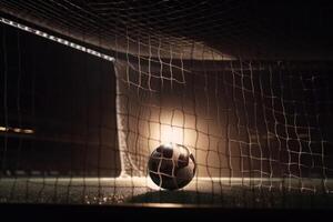 A football goal without a goalkeeper - a ball flying into the net - dark light from spotlights created with technology. photo