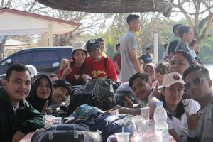 Atambua, Nusa Tenggara Timur, 2022 Tourists sitting around a table where there are lots of bags, drinking water and helmets photo