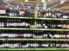 Blurred background, bottles of wine on an alcohol stand in a supermarket. photo