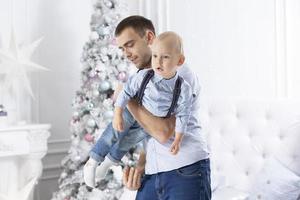 padre y niño jugar en contra el antecedentes de un Navidad árbol. hombre y hijo en el nuevo año. foto