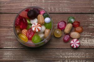 Candies in a jar on a wooden background. Multi-colored caramel. Sweets. photo