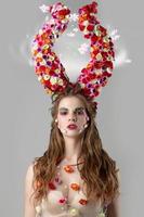 Beautiful girl with flower horns. Malificent. Spring beauty. Woman flower.Goddess of flowers Flora. photo