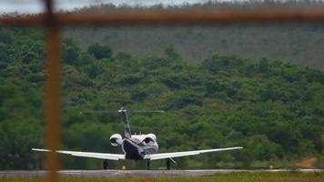 bak- se av privat jet plan tar av. företag jet acceleration och avresa. flygplan på grön kullar bakgrund, flygfält i de tropikerna video