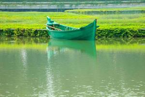 A green boat without passengers was parked on the edge of the lake. photo