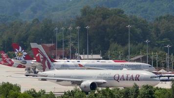 phuket, tailandia 30 de noviembre de 2019 - qatar airways boeing 777 rodando antes de la salida y airbus a330 nordwind en servicio, aeropuerto internacional de phuket. video