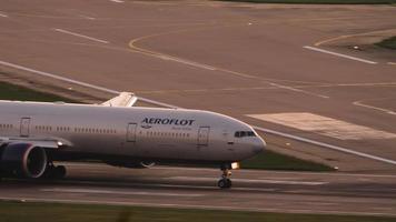 SOCHI, RUSSIA JULY 30, 2022 - Boeing 777 of Aeroflot braking after landing at Sochi airport at sunset. Cinematic shot of passenger airliner arrival. Tourism and travel concept video