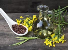 canola aceite, flores y semillas en rústico madera foto