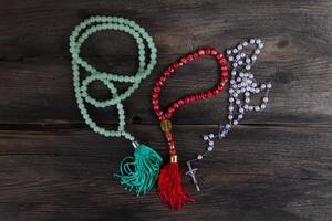 set of rosaries of various religions on rustic wood photo