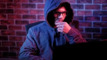 hooded hacker working on laptop stealing personal data in dark room video