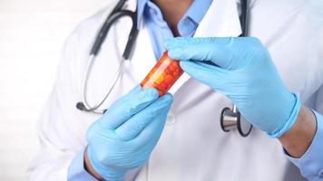 doctor in scrubs looking at container with medicine pills video