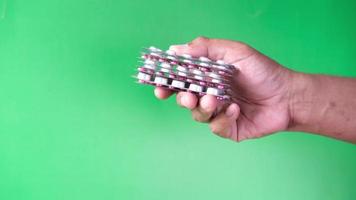 Close up of hand holding blister packs against green background video