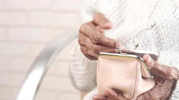 Senior woman hand saving coins in a purse video