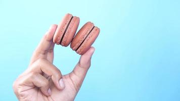 dichtbij omhoog van Holding bitterkoekjes tegen blauw achtergrond video