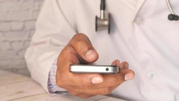 man wearing white lab coat at doctors office using smartphone video