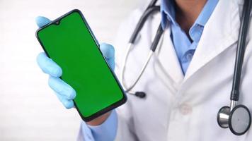 médico segurando verde tela Smartphone dentro mão, conectados cadastro para médico video