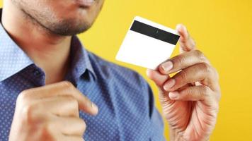 A guy standing isolated over yellow background holding a credit card video