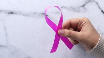 Hand holding pink color ribbon close up video