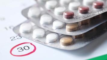 Birth control pills and calendar on wooden background, close up video