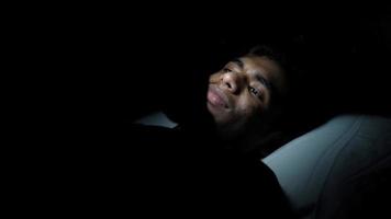 giovane uomo nel il buio posa utilizzando smartphone video