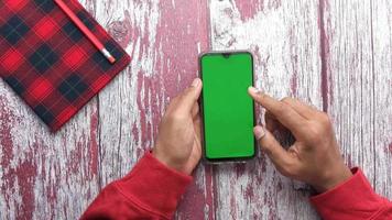 Top view of man hand using smart phone with green screen video