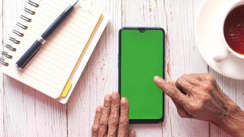 senior woman texting with her pointhe on a green screen phone video