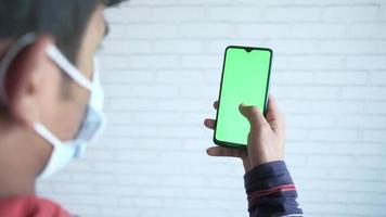 alto ángulo ver de persona mano utilizando inteligente teléfono con verde pantalla video