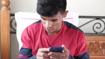 jovem na cama usando telefone inteligente à noite video