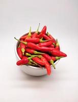 Chili peppers or Cayenne pepper or Cabe rawit in a bowl isolated on white background. photo