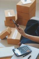 Entrepreneurs Small Business SME Independent men work at home Use smartphones and laptops for commercial checking, online marketing, packing boxes, SME sellers, concept, e-commerce team, online sales photo