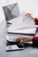 Asian Business woman using calculator and laptop for doing math finance on an office desk, tax, report, accounting, statistics, and analytical research concept photo