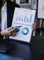 Asian Business woman using calculator and laptop for doing math finance on an office desk, tax, report, accounting, statistics, and analytical research concept photo