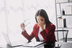 Asian women are stressed while working on laptop, Tired asian businesswoman with headache at office, feeling sick at work, copy space photo