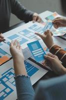 Close up ux developer and ui designer brainstorming about mobile app interface wireframe design on table with customer breif and color code at modern office.Creative digital development agency photo