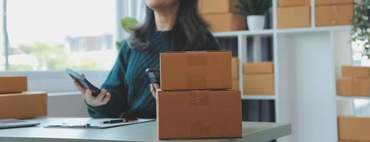 Entrepreneurs Small Business SME Independent men work at home Use smartphones and laptops for commercial checking, online marketing, packing boxes, SME sellers, concept, e-commerce team, online sales photo